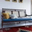 This image showcases a rosewood sofa set, a pure example of classic Indian furniture design, including a three-seater and two single-seater chairs featuring handwoven cane backrests, carved legs, grassy work on the sides, and ample sleek hand rests