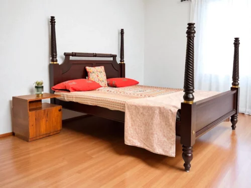 This Half Canopy King Size Poster Bed is masterfully crafted from premium Kerala Rosewood, showcasing exceptional craftsmanship and a truly unique design. The bed features intricate spiral carvings along the posts and headboard, with brass rings adorning the canopy for a regal touch. A finely carved wooden rod crowns the headboard, adding depth and detail. The traditional kadachil leg design enhances its heritage appeal, while the overall structure exudes strength, elegance, and timeless artistry—perfect for those who appreciate classic luxury in their bedroom space.