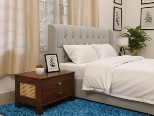 Teak wood bedside table with two drawers, ornate metal handles, and handcrafted cane panel, placed on a blue rug in a cozy interior