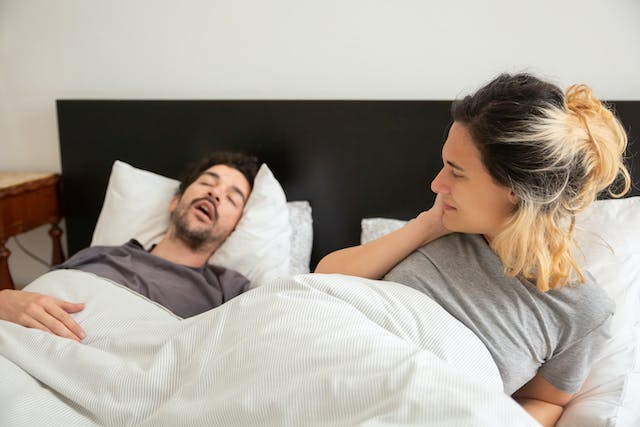 a snorer on a bed disturbing his partner