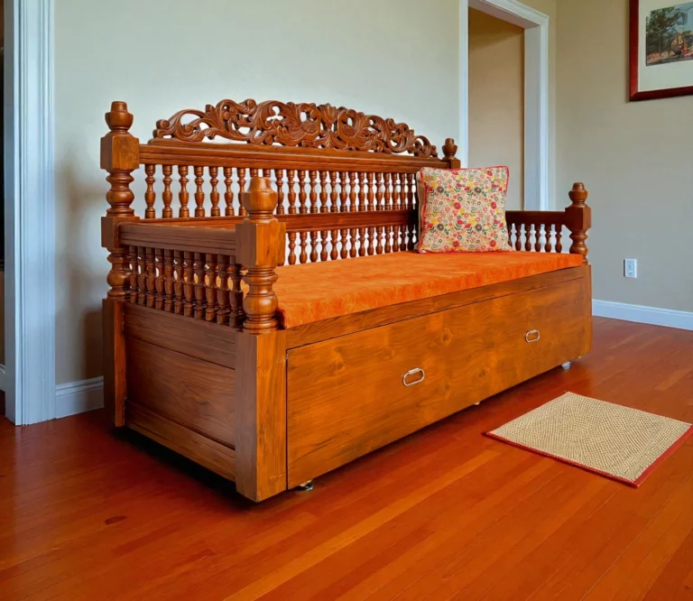 This Teak Wood Sofa Cum Bed is a beautifully crafted piece made exclusively from solid Kerala Teak wood, showcasing exceptional craftsmanship and traditional artistry. The backrest features intricate kadachil work, while the cot is adorned with elegant carvings, including a striking peacock motif. The sides are designed with comfortable hand rests and additional kadachil detailing, offering both style and support. Spacious enough to seat three adults comfortably, the sofa smoothly transforms into a Queen size bed with a strong, stable pull-out mechanism—providing ample space for restful sleep. It comes with a plush cushion set that can be used or removed as preferred, and is available in a variety of fabric color options to suit your interior. A perfect fusion of heritage design and modern utility.