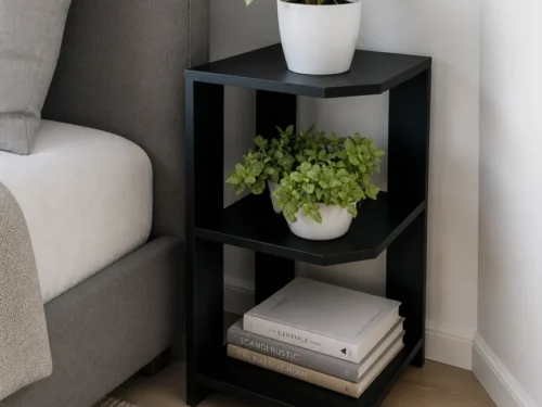 Black 3 tier corner shelf side table in engineering wood beside a bed